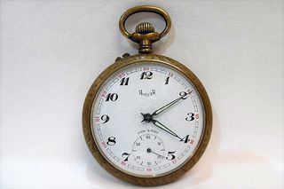 Παλιό μπρούτζινο ρολόι τσέπης με ανάγλυφο σχέδιο στο πίσω μέρος του.