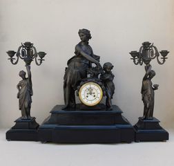 Ρολόι μεταλλικό με αγάλματα Αφροδίτης και Έρωτα, μαρμάρινη βάση και δυο πεντάκερα κηροπήγια.