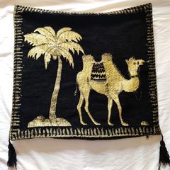Μαξιλαροθήκη αφρικάνα με θέμα φοίνικα και καμήλα σε μαύρο φόντο και με κλωστή σε χρυσό χρώμα.