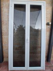 Ανοιγόμενη δίφυλλη μπαλκονόπορτα αλουμινίου με ανάκληση με φυμε τζάμι και σίτα