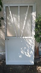 Πόρτα αλουμινίου εισόδου με μισό πάνελ και μισό τζάμι.